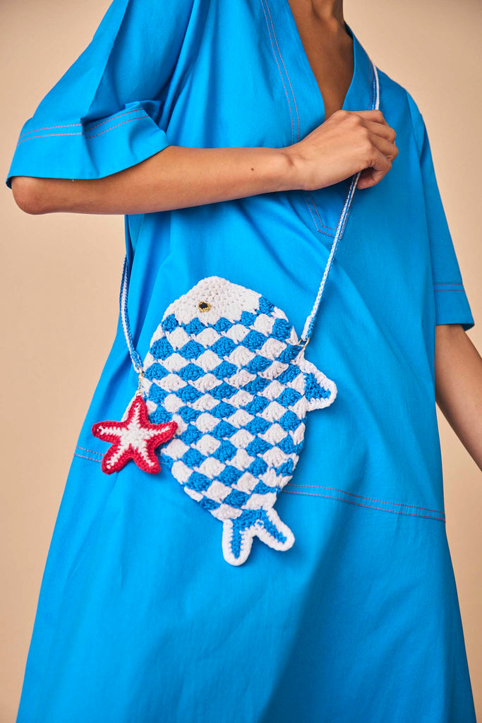 The fish bag is hand made in Bolivia with a starfish charm, a snap closure, and long shoulder strap.