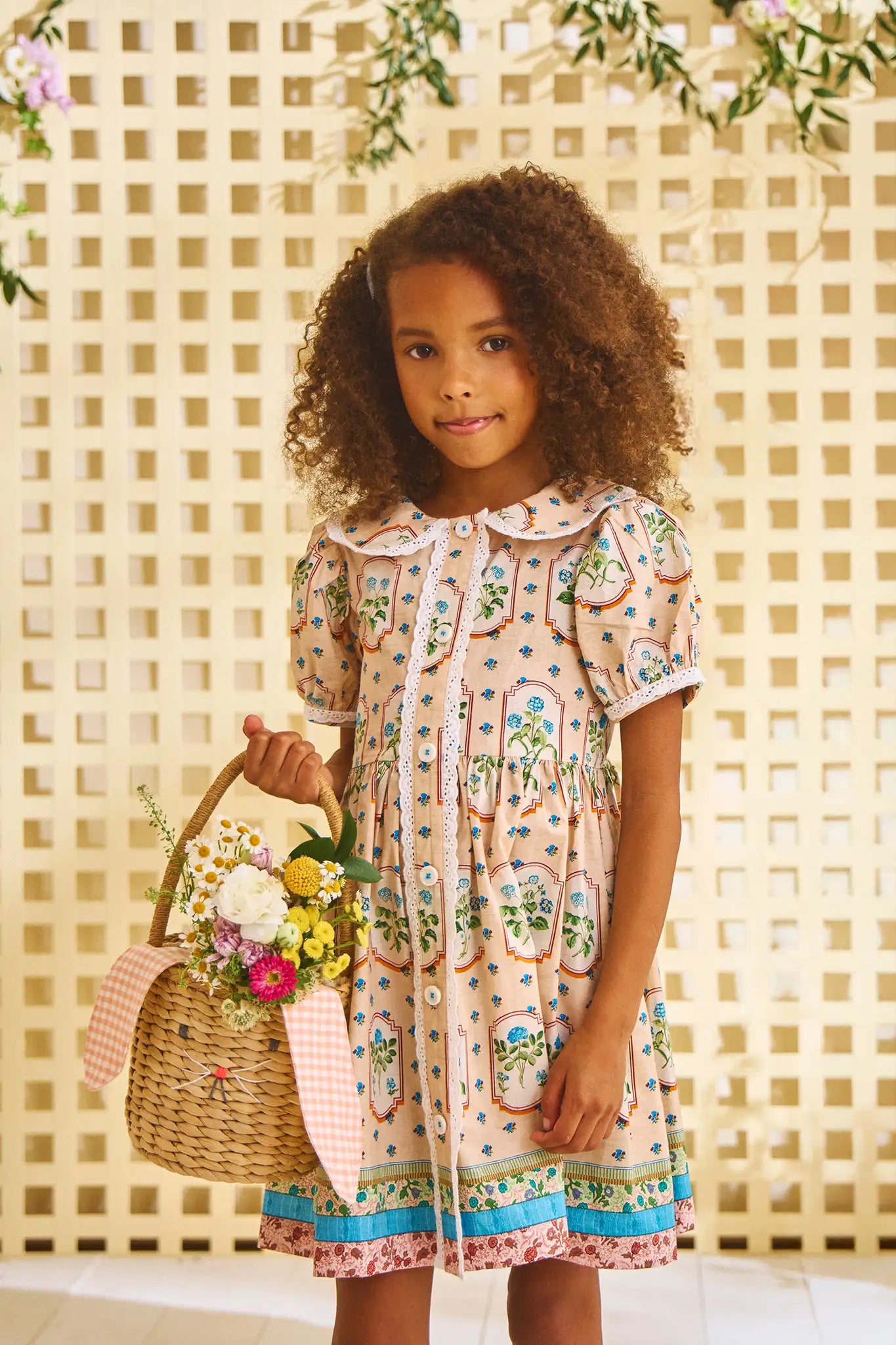 The Sally Dress has a peter pan collar, short puff sleeves, eyelet trim and front button placket.