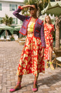 A full-length pleated orange and yellow printed skirt with a fixed waistband and functional pockets.