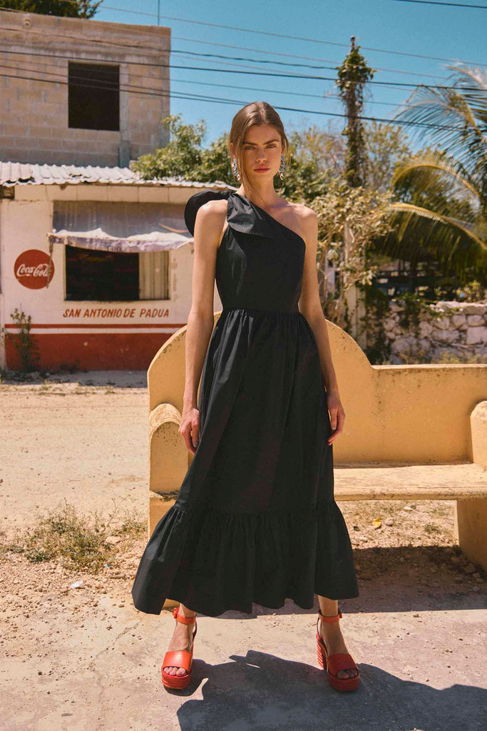 The Alana Dress has a one-shoulder neckline with a bow, a fitted waist and tiered seams.