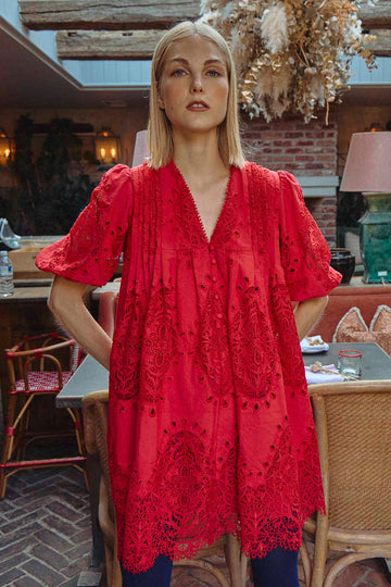 The Alden Dress in scarlet lace has a v-neckline, elbow-length puff sleeves, and a pull-over design.