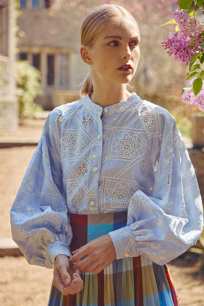 The Alma eyelet shirt has a round neckline, long raglan sleeves, and intricate crochet buttons.