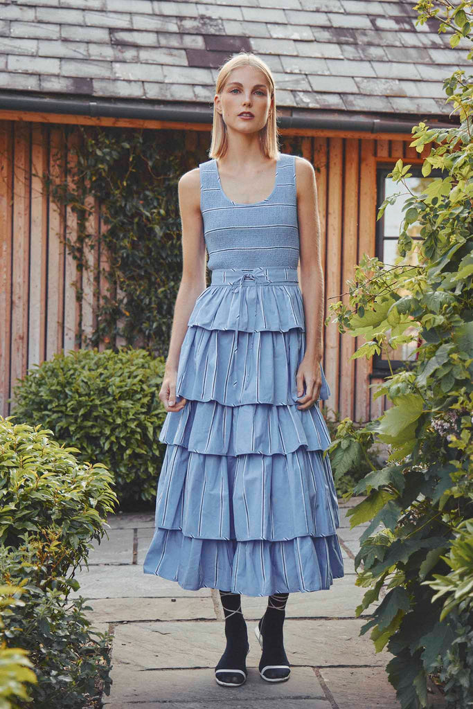The Andrea tiered dress has a scoop neck, a smocked bodice, with a fitted waist and a belt.