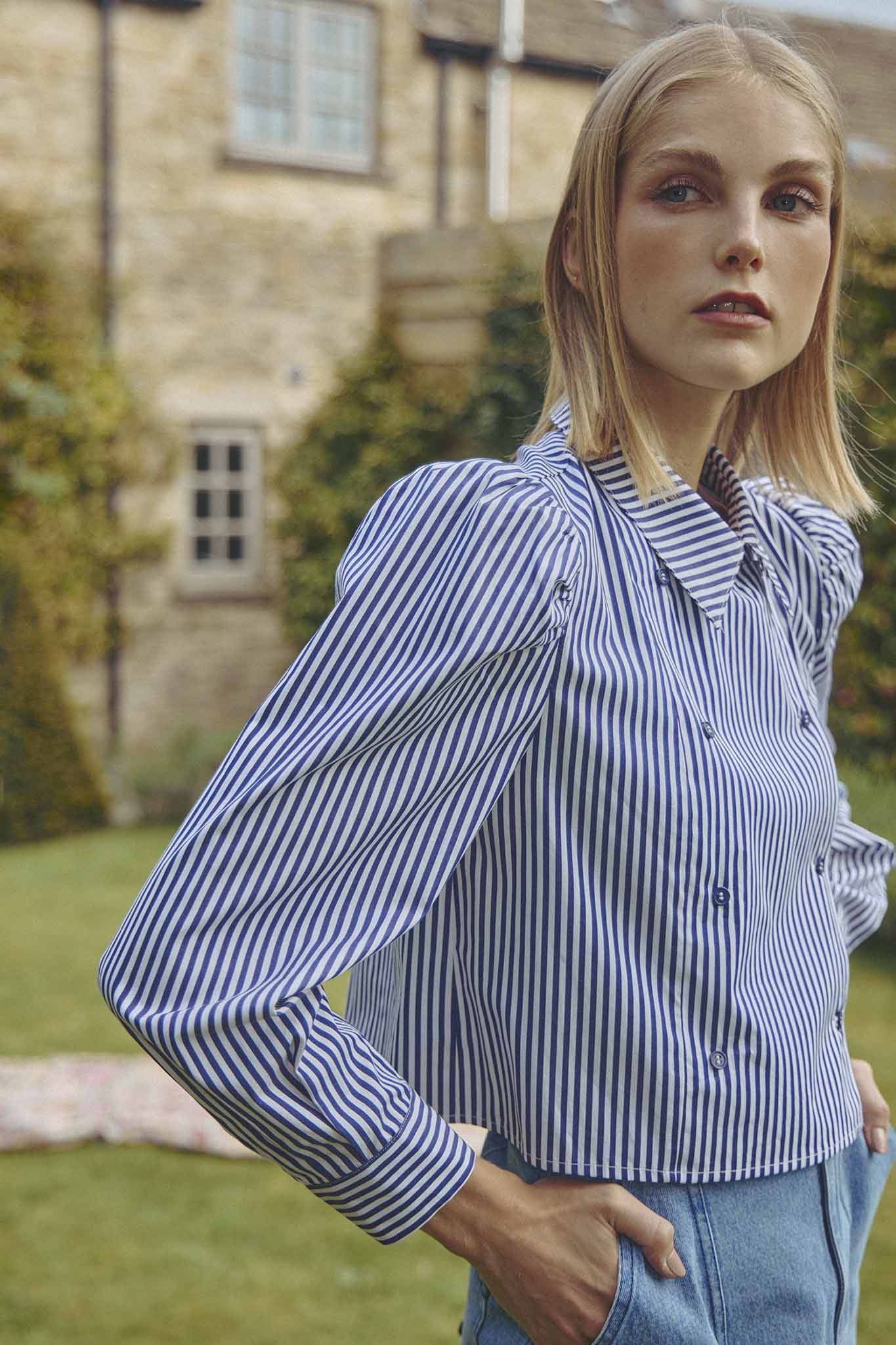 The cropped Annette Shirt is a striped long-sleeve with a double-breasted button placket.