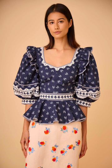 The Blayne Top has a princess neckline, oversized puff sleeves, a cinched waist, and a peplum hem. 
