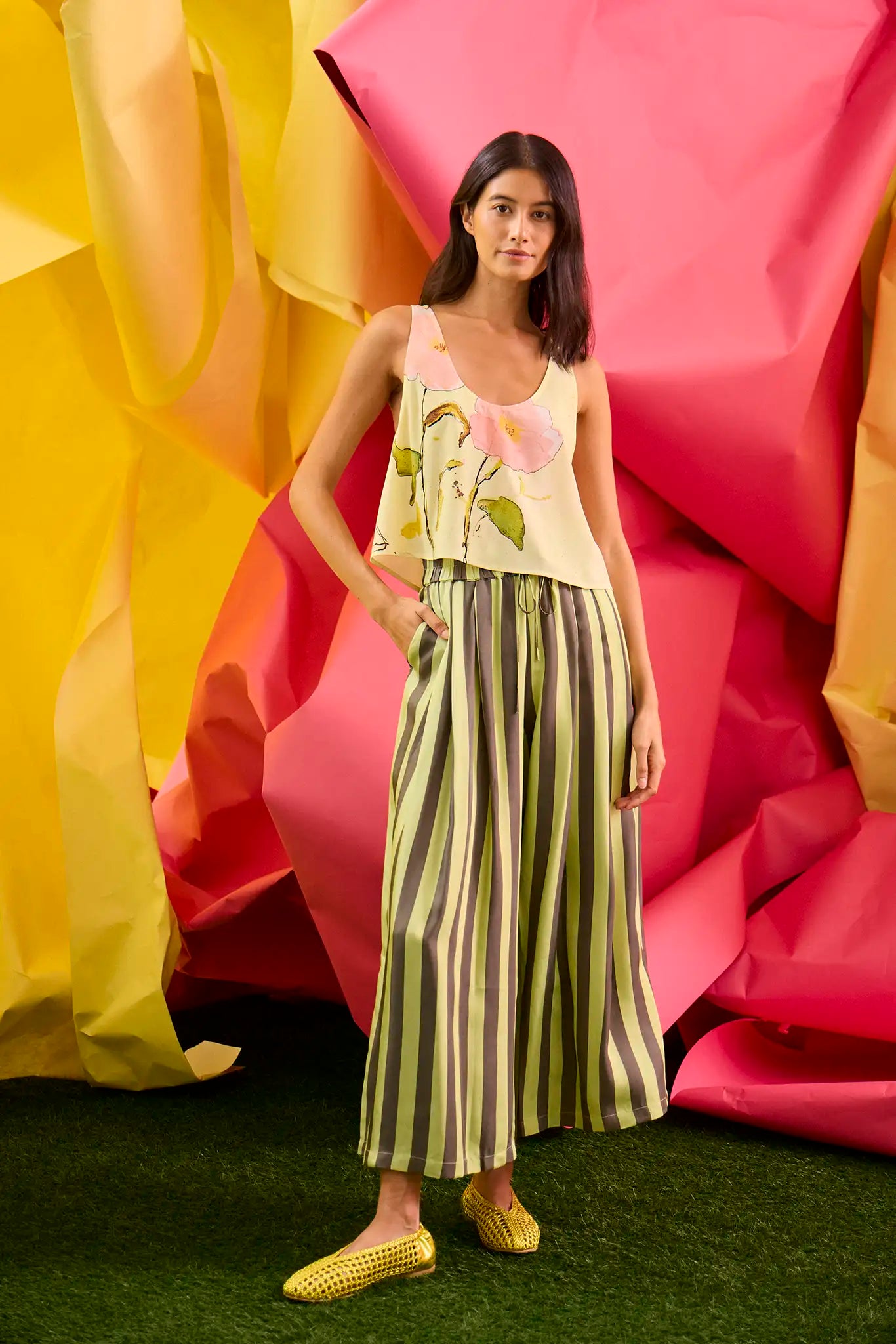 The Carsyn Tank in Quiet Bloom paired with Cyprus Pant in Evergreen Stripe in front of colorful wall.