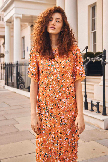 The Constance dress has a crew neckline, short sleeves and hand beaded orange sequins throughout.