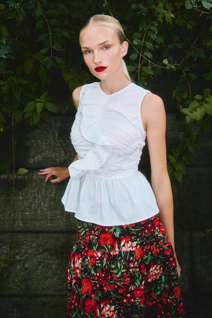 The Doering Top is a fitted V-neck silhouette with ruffles, shirring, and a peplum waist. 