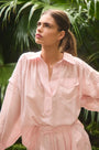 The Evangeline Shirt in Pink Sand paired with the matching Whisper Pant with palm leaves background.