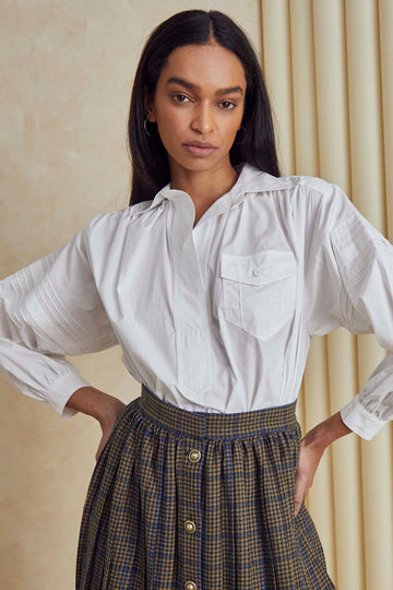 Evangeline is a collared blouse with pleat detailing along the sleeve, and a back yoke seam.