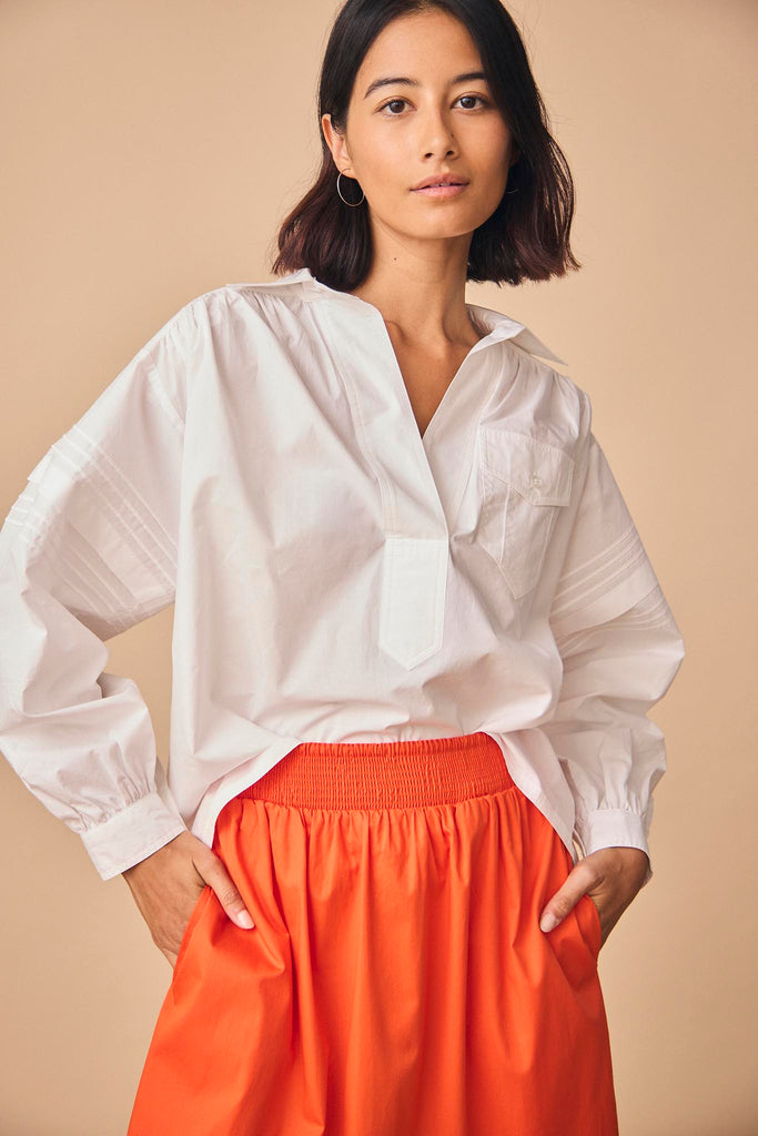 Evangeline is a collared shirt with pleat detailing along the sleeve, and a back yoke seam.