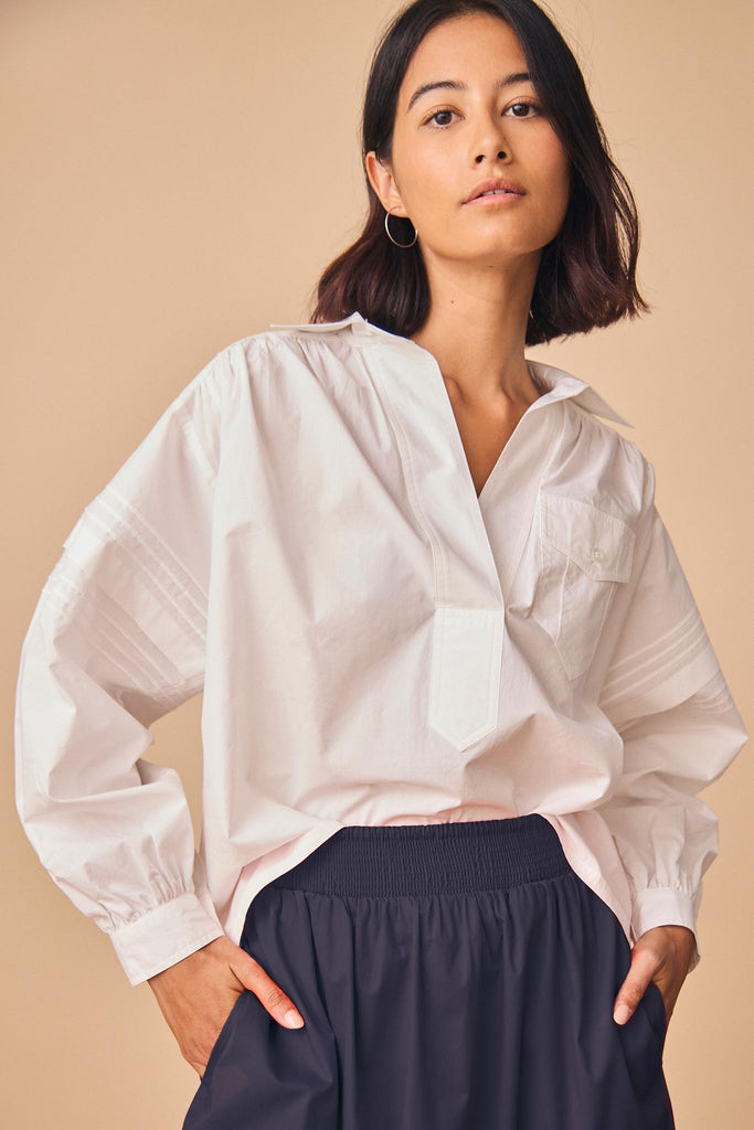 Evangeline is a collared shirt with pleat detailing along the sleeve, and a back yoke seam.