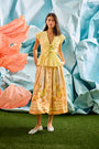 Eva Skirt in Still Life Symphony paired with Everly Top in Lemon Meringue, in front of colorful wall.