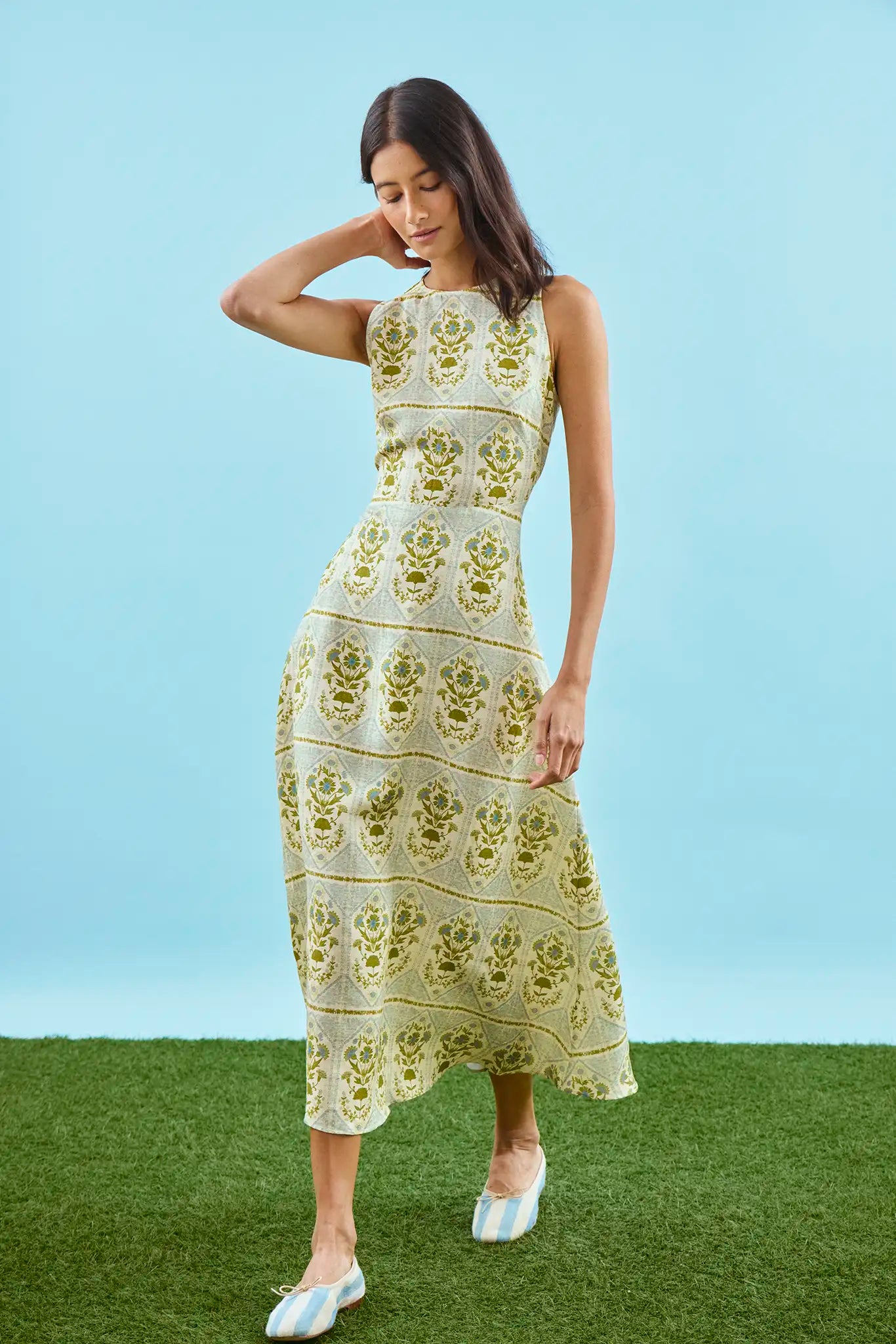 Faith Dress in Green Trellis modeled in front of blue wall.