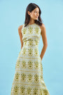 Faith Dress in Green Trellis modeled in front of blue wall.