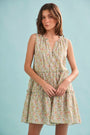 The Fawn Dress in Coral Multi paired with pale yellow shoes on a blue background.