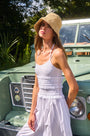 The Francie Dress in white paired with straw hat in sun in front of green car