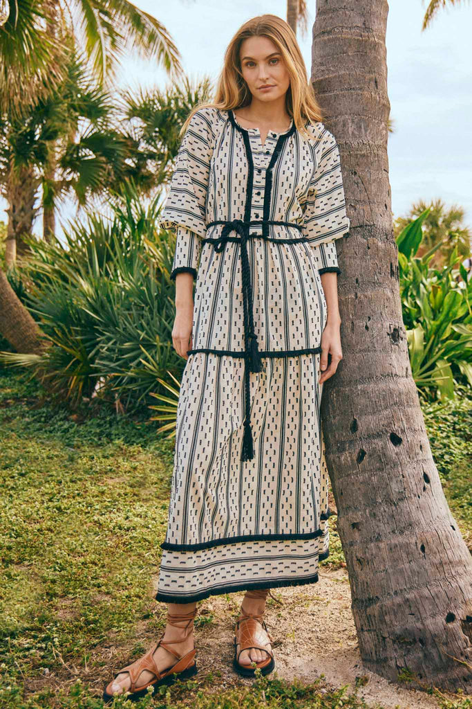A long sleeve maxi dress with adorned fringe, and a textured pattern with large blouson sleeves.