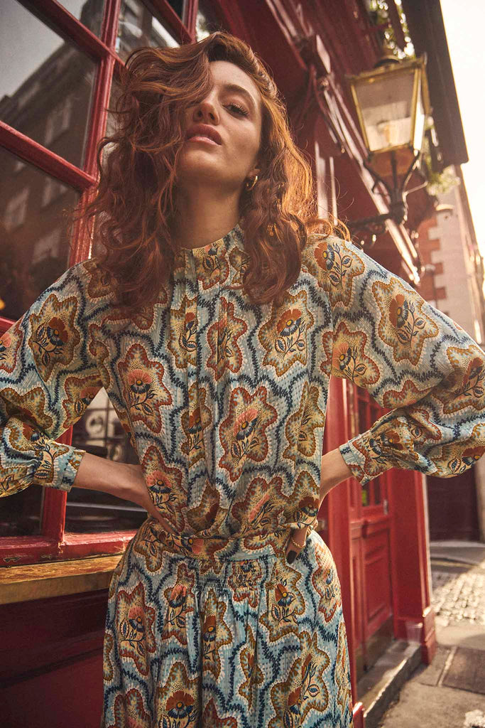 The Graham top has a mock pleated neckline, blouson sleeves with button cuffs and a hidden zipper.