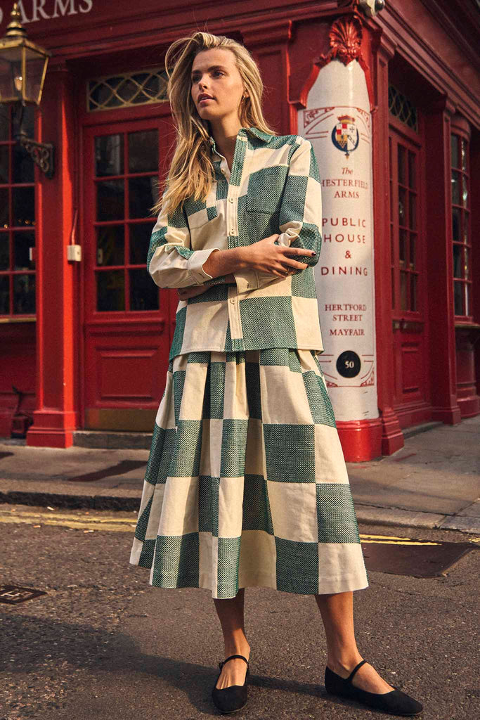 The Alexis skirt has a full pleated skirt, banded waist, center back zipper and side seam pockets.