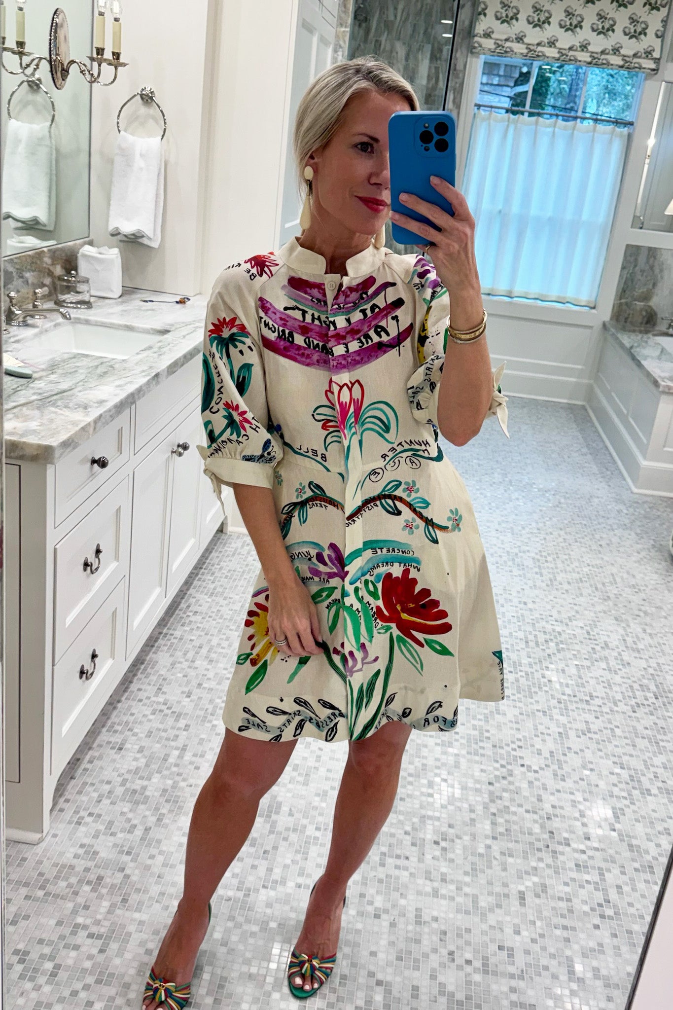 A mini dress with colorful print, front-buttons, mandarin collar, and elbow length sleeves with ties.