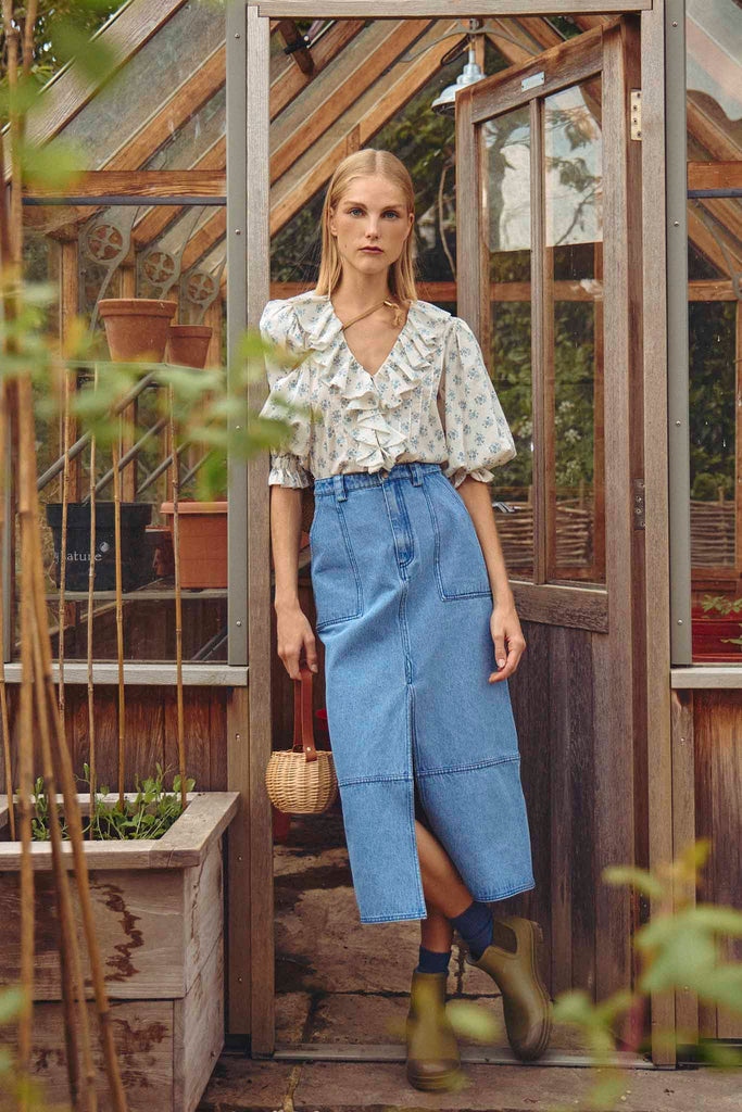 The Parke denim midi skirt showcases a stylish front vent and belt loops at the waist.