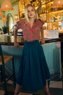 Petrol green pleated maxi skirt with side-seam zipper, fixed waistband, and functional pockets.