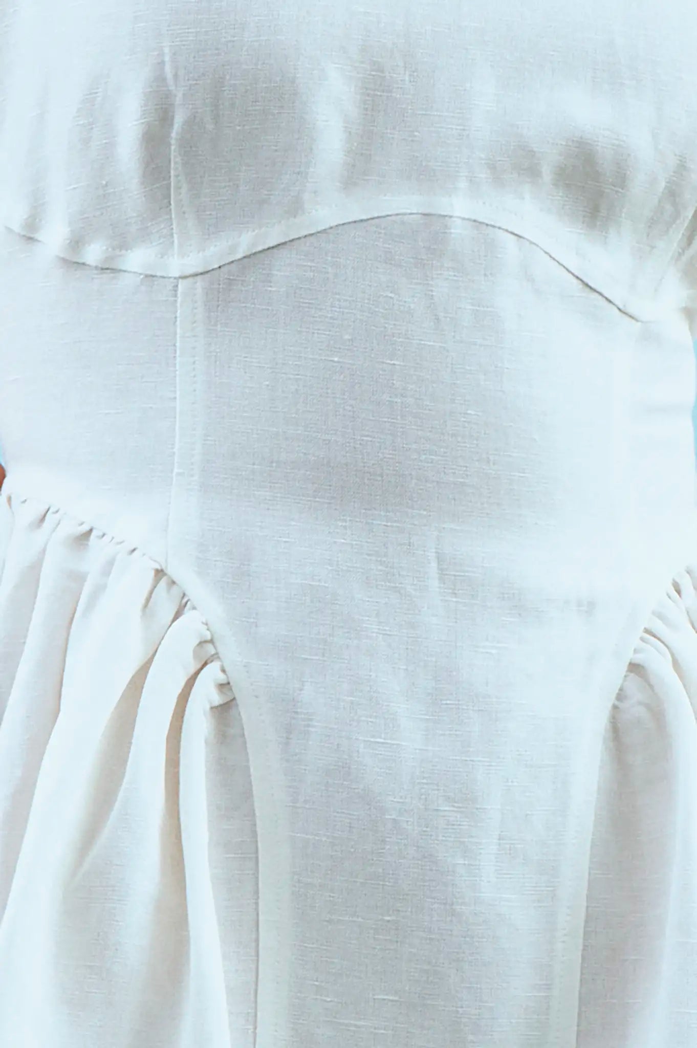 Close up of white linen mini dress with structured bustier bodice.