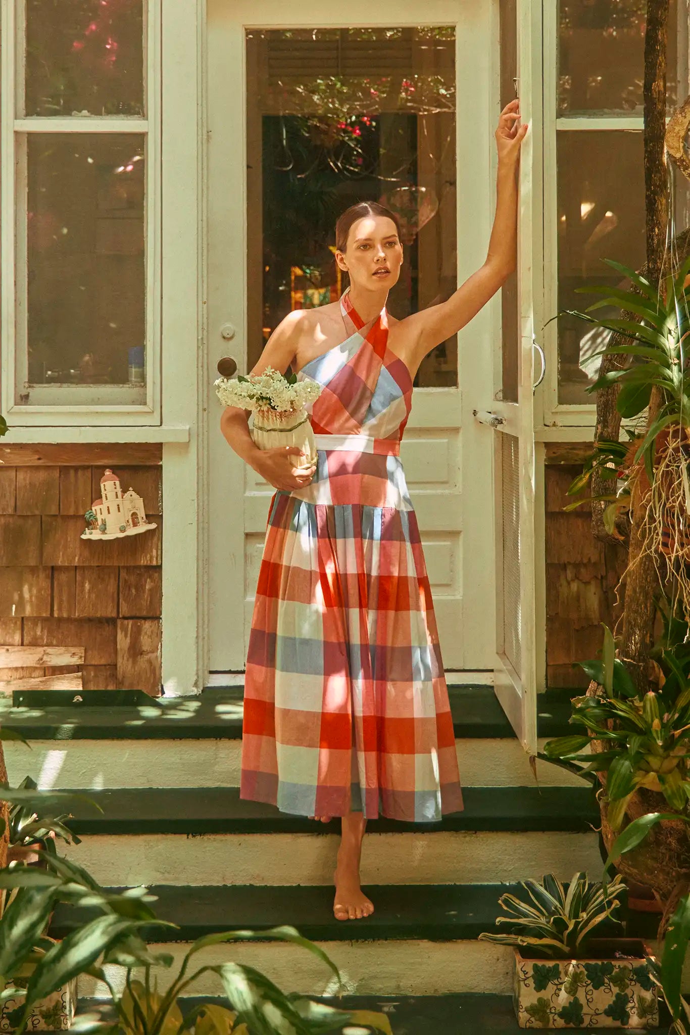 The Lennon Dress has a cross-front halter neckline and full pleated skirt in an oversized plaid.