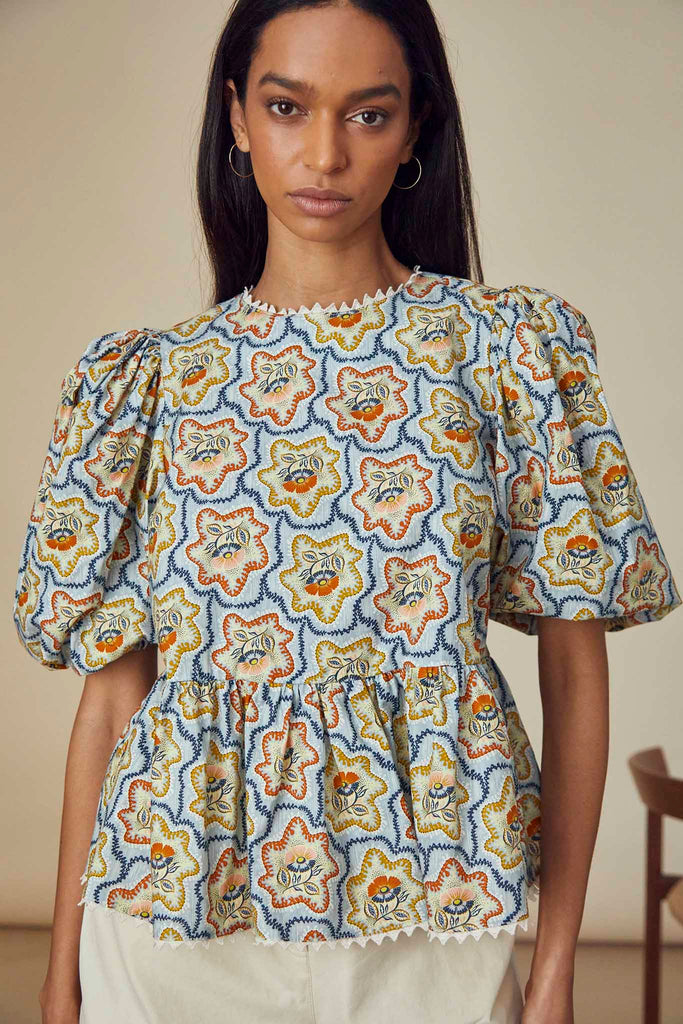 The Lenny top has a round neckline, puff sleeves and a peplum silhouette with flounce hem.