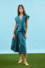 Petrol green pleated maxi skirt with side-seam zipper, fixed waistband, and functional pockets.