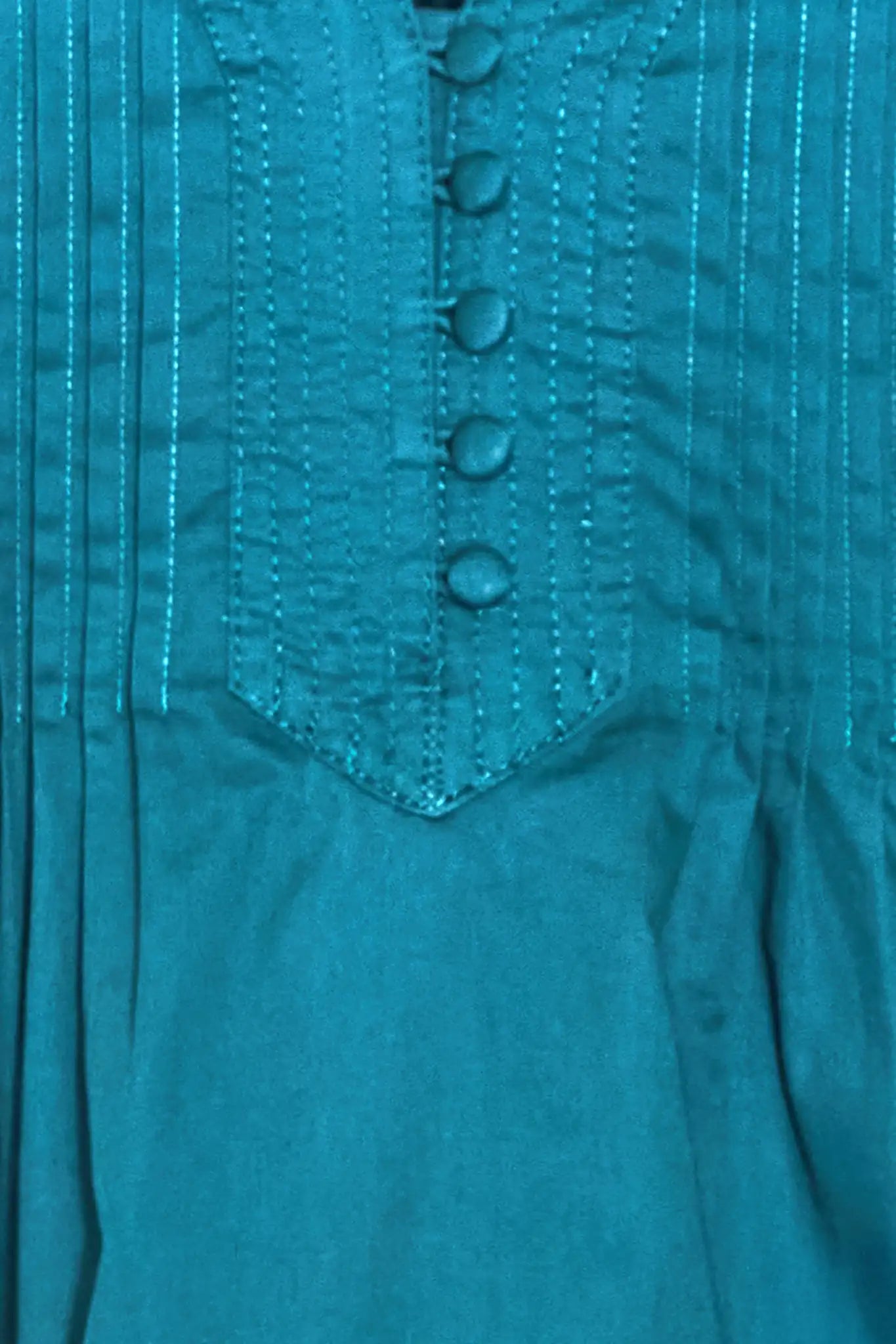 A cropped, boxy top, v-neckline, delicate pintuck detailing and short banded sleeve in petrol green.