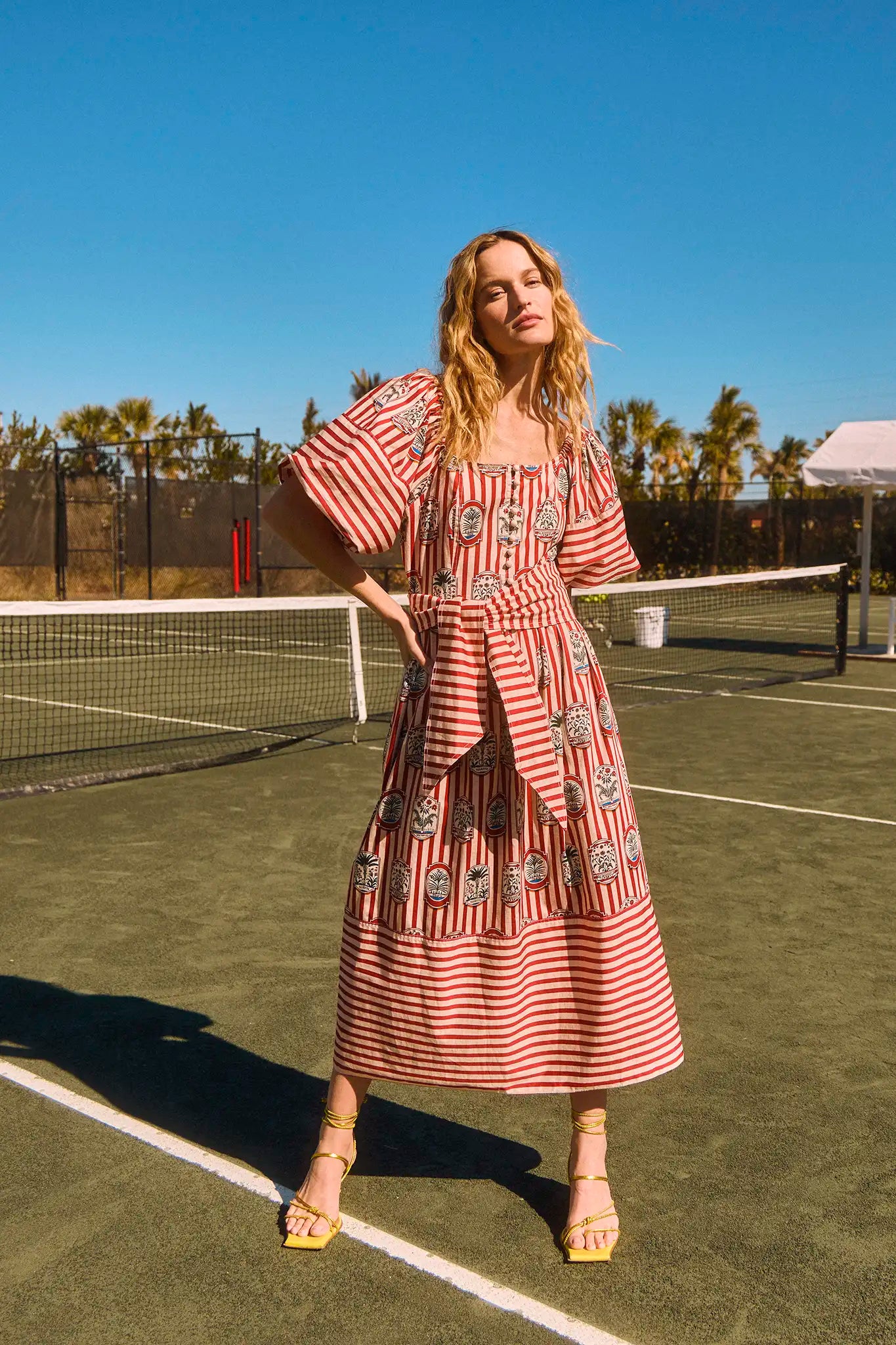 The Lucy midi dress has a square scoop neck, puff sleeves, front button placket, and a self belt.