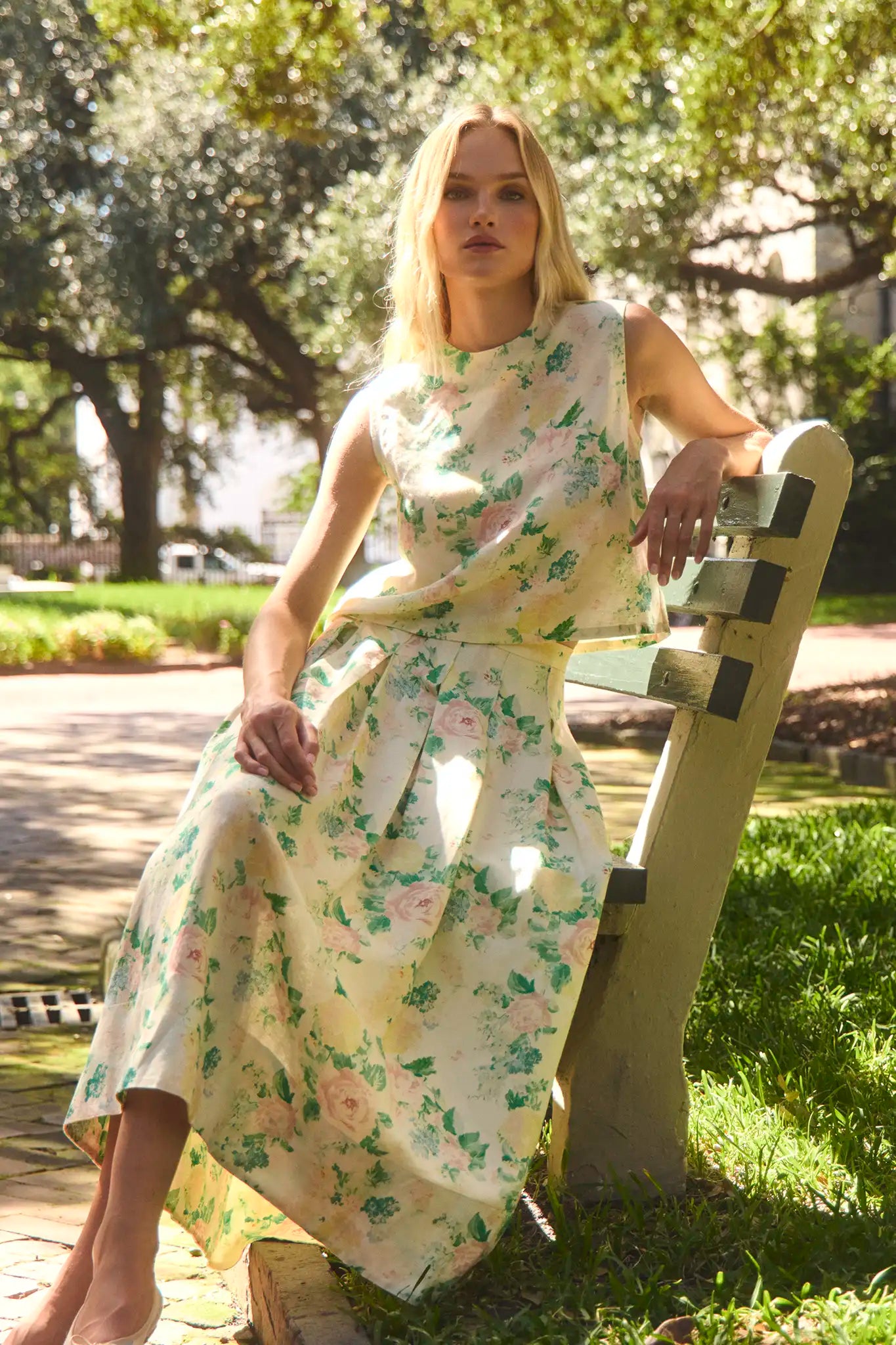 The Alexis Skirt in Garden Rose Peony paired with matching Manning Top sitting on bench in sun.