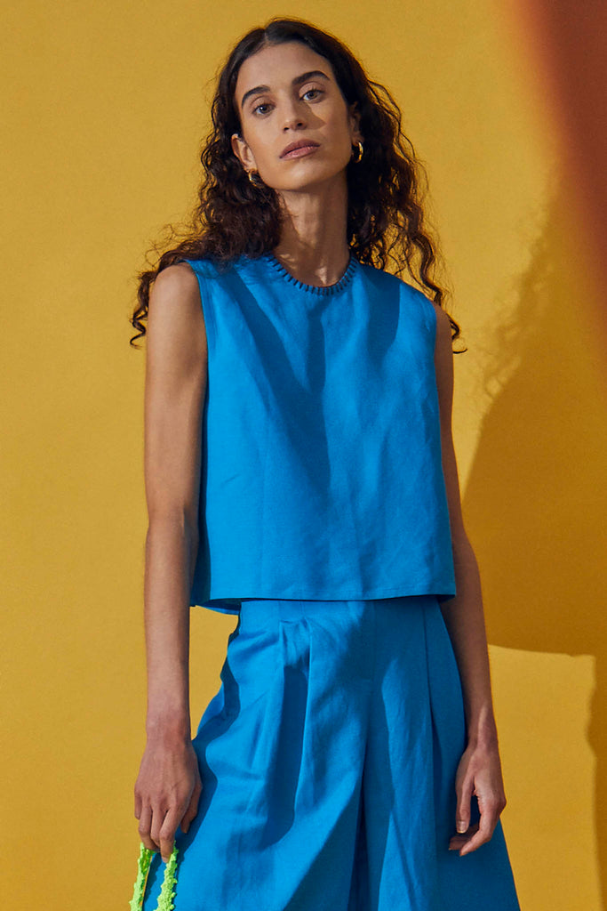 A sleeveless linen crop top with a boxy fit and a crew neckline with contrast whipstitch detailing.