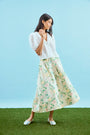 The Alexis Skirt in Garden Rose Peony paired with white Mare Top with blue background.