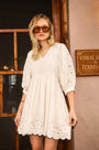 The Maya Dress in white, paired with brown sunglasses.