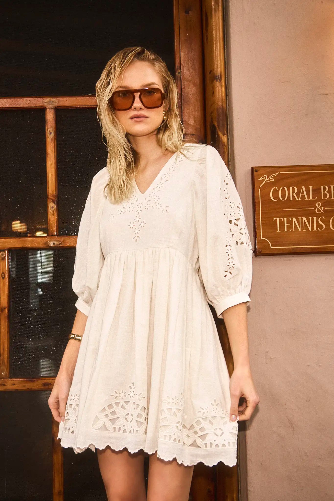 The Maya Dress in white, paired with brown sunglasses.