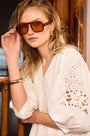 The Maya Dress in white, paired with brown sunglasses.