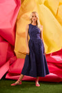 A sleeveless midi navy dress with a fitted bustier bodice, crew neckline, and a bustled full skirt.
