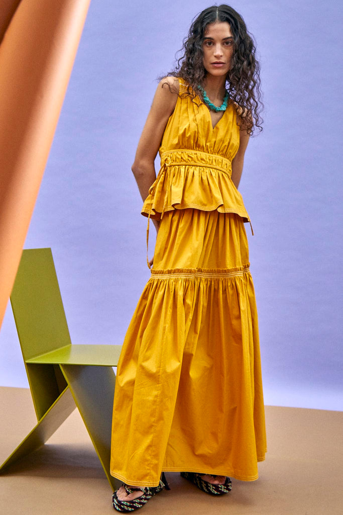 A tiered maxi skirt with ruffle seams, a shirred band at the waistline, and self-tie detailing.
