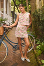 The Britt Mini Skirt in Magnolia Grove Jacquard paired with the Rebecca Top, leaning against a bike.