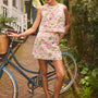 The Britt Mini Skirt in Magnolia Grove Jacquard paired with the Rebecca Top, leaning against a bike.