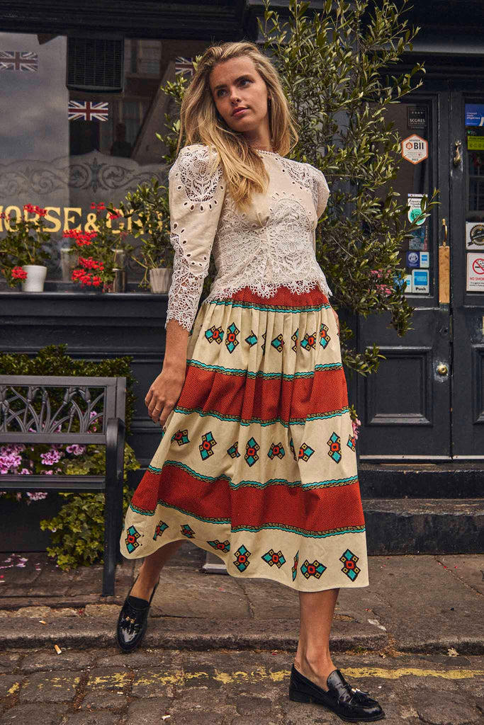The Rue midi skirt has a covered waistband, full pleated skirt and back center zipper.