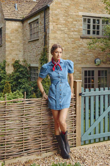 The Robinson denim dress has paneled seams, a shirttail hem, and snap a front closure.