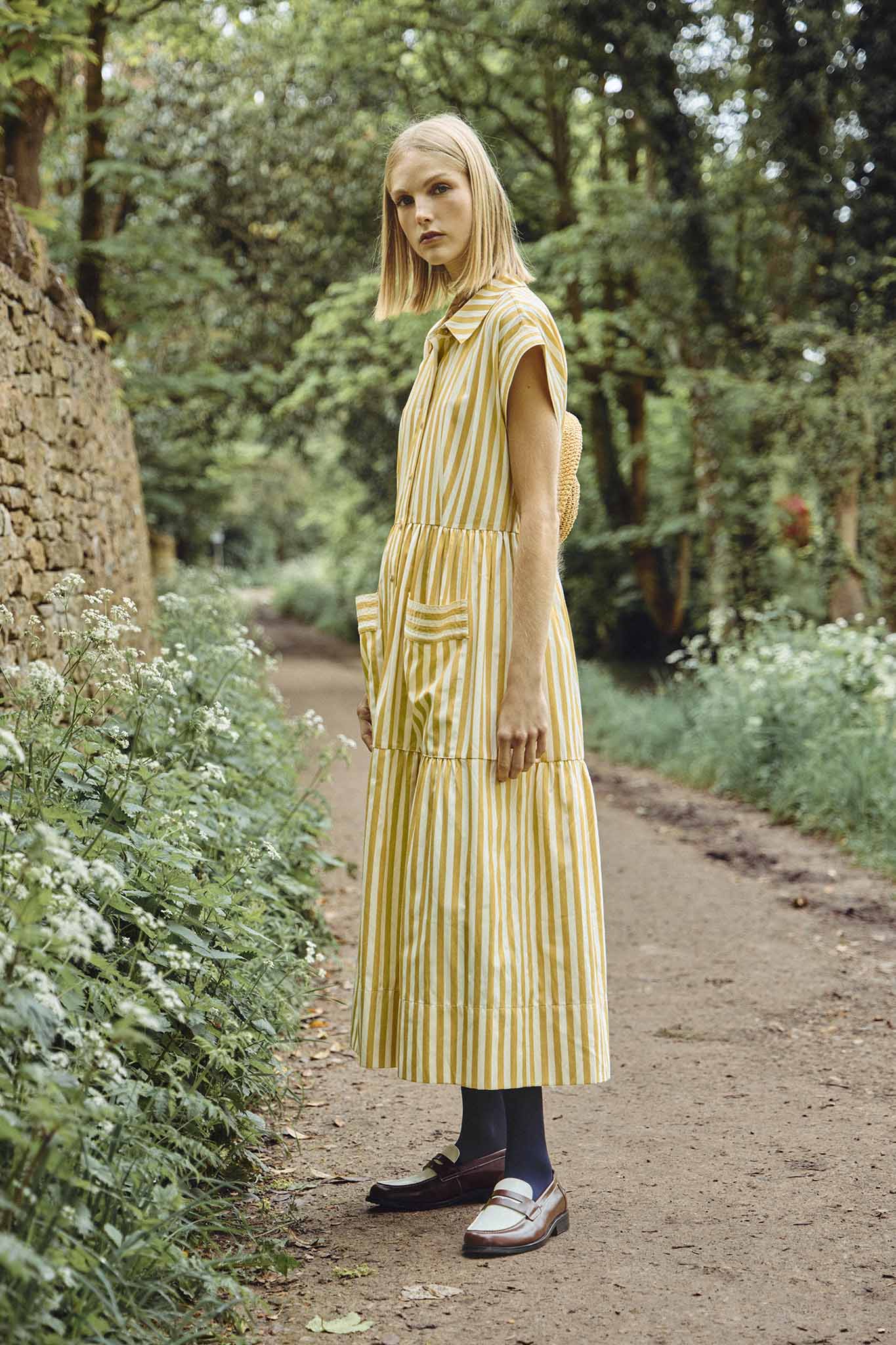 This Sarah dress is a shirt dress with banded cap sleeves, a tiered skirt, and patch front pockets.