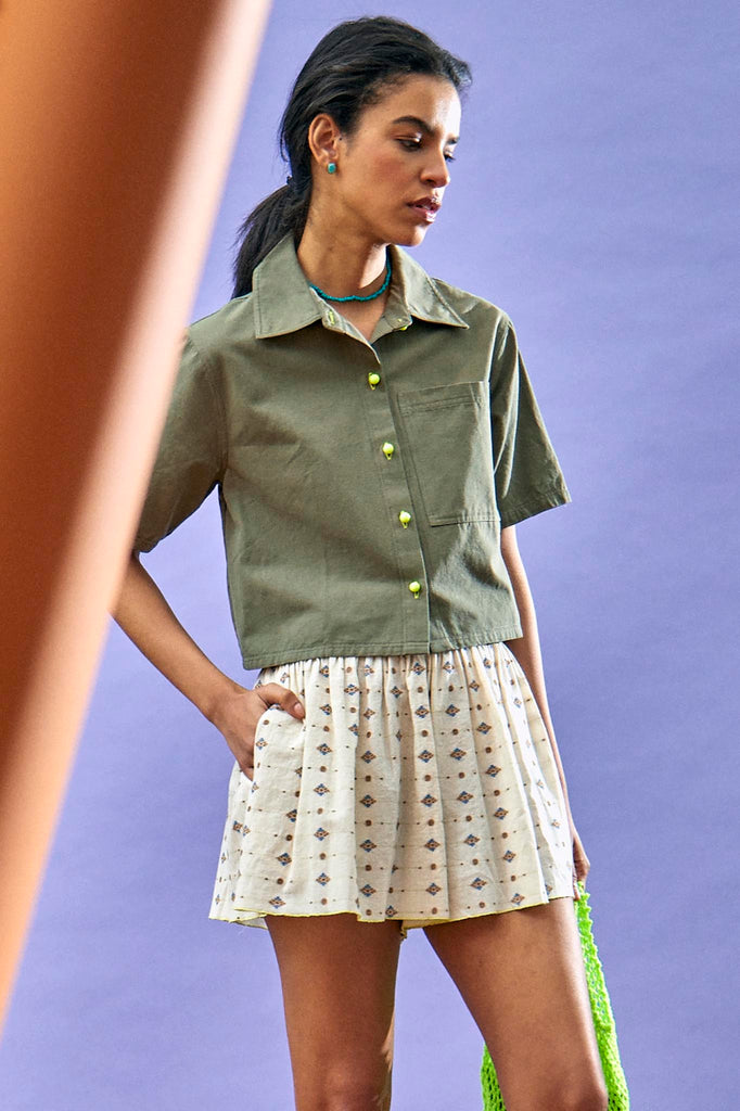 The Scout Top in Army Green features a camp collar, wide cut short sleeves, and neon yellow buttons.