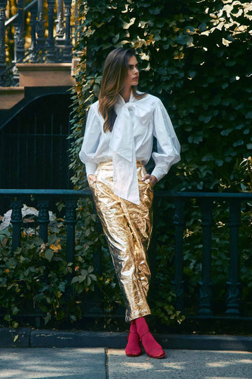 The Haskell Pant in gold faux leather has a fitted waist, side seam zipper, and slash front pockets.