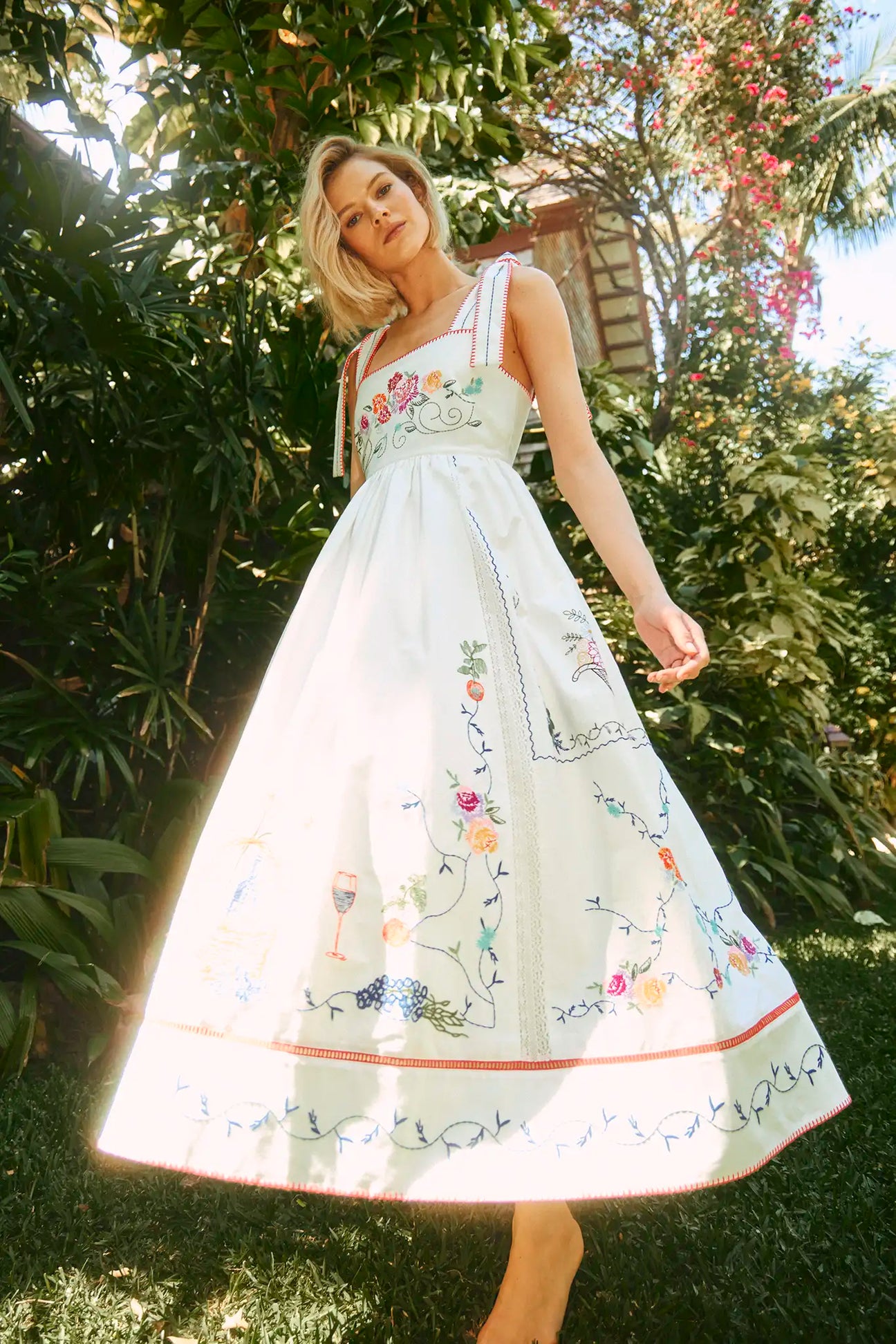 The Stefy Dress has tie straps, an empire waist, colorful embroidery, lace trim, and stitch edging.