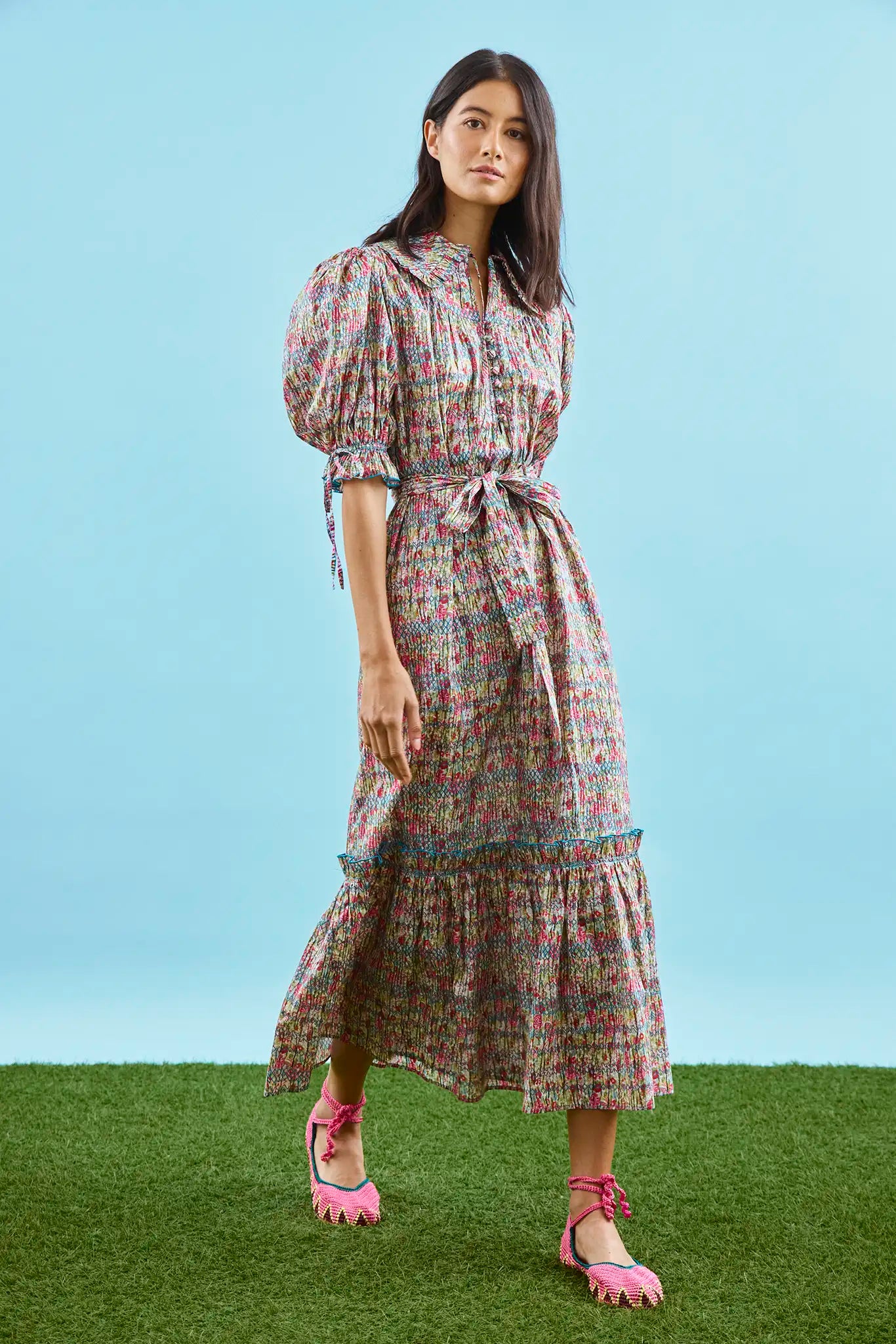 An open V-neckline with a ruffled collar, elbow length puff sleeves with tie details.